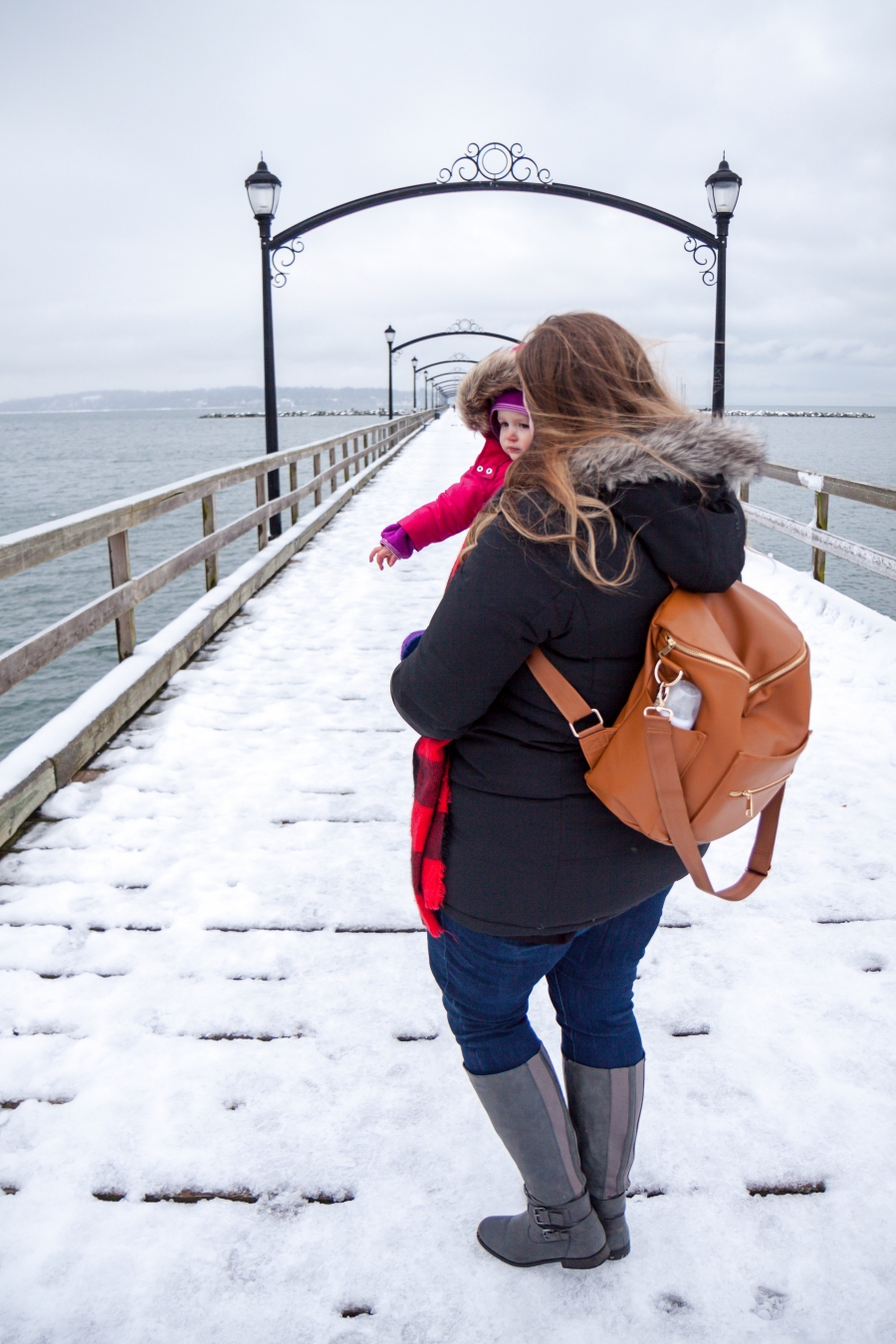 Fawn Design diaper bag blog review, what's in my diaper bag. Mother holding her daughter on pier of White Rock while wearing Fawn Design diaper bag in brown.
